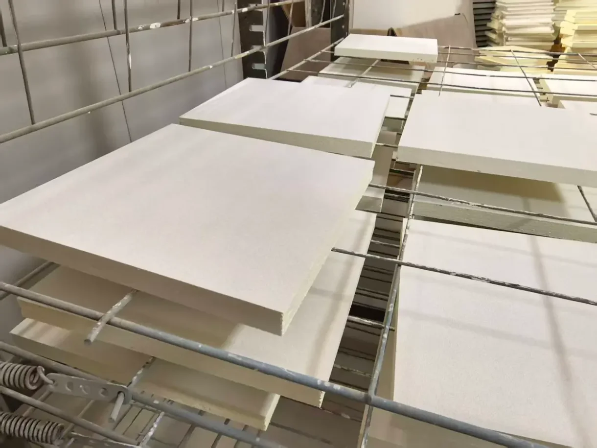 White fiberglass acoustic ceiling panels during factory surface finishing and production