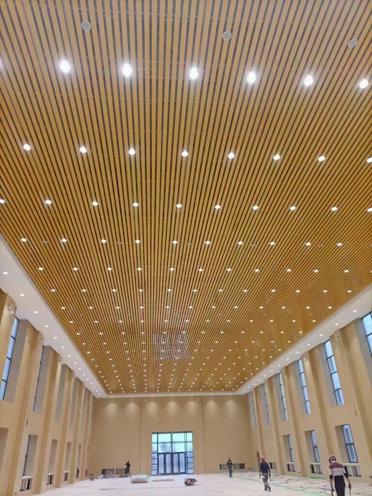 Wood grain U-shaped aluminum baffle ceiling with integrated lighting in a public hall