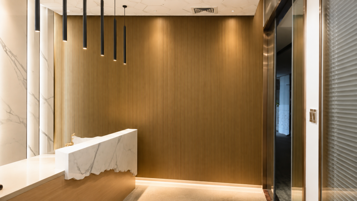 Wood grain fluted aluminum wall panels installed as a modern warm-toned feature wall in a high-end commercial reception lobby.