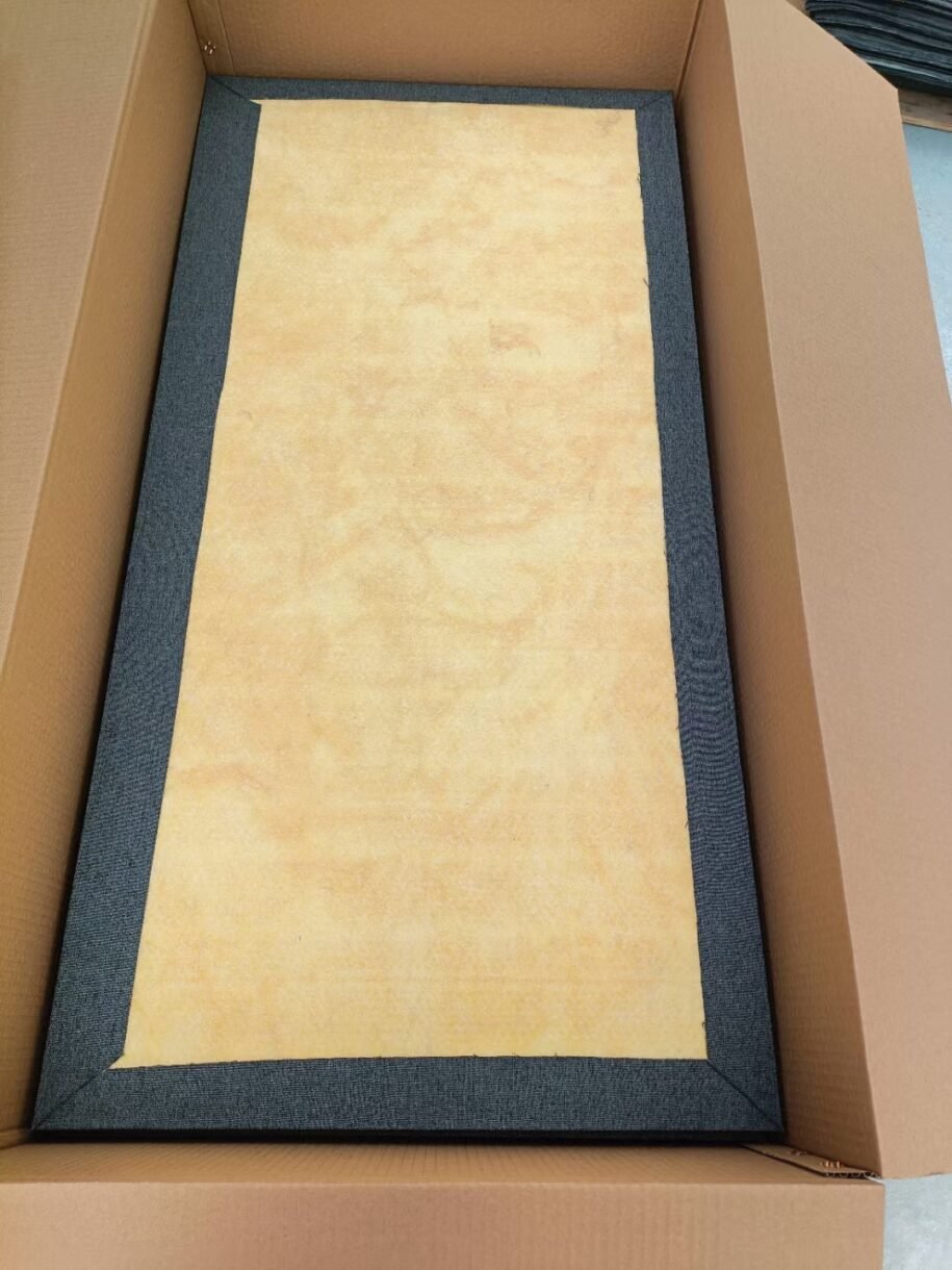 Back view of a fabric-wrapped fiberglass acoustic panel in its packaging, revealing the high-density yellow fiberglass core and neatly folded fabric edges.