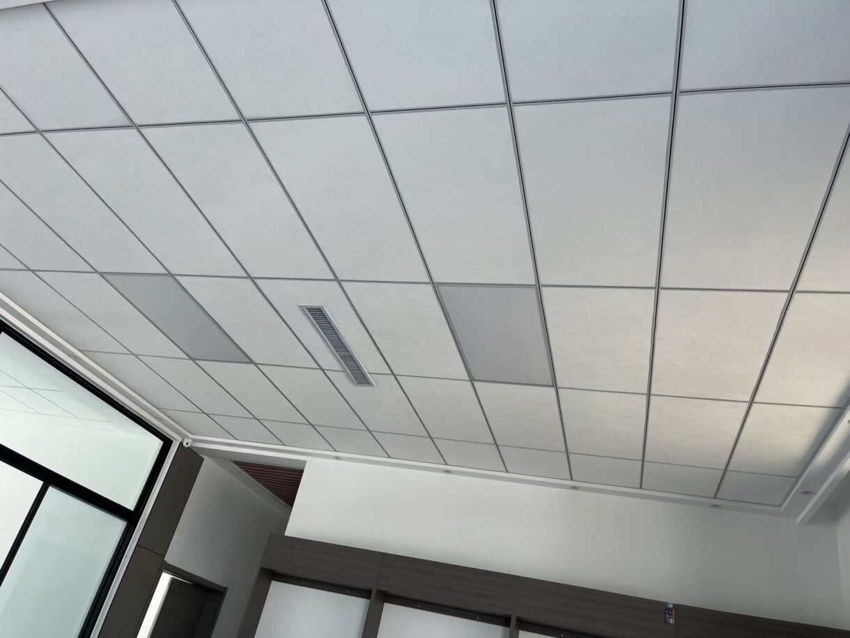 White fiberglass acoustic ceiling panels installed in a standard commercial drop ceiling grid.