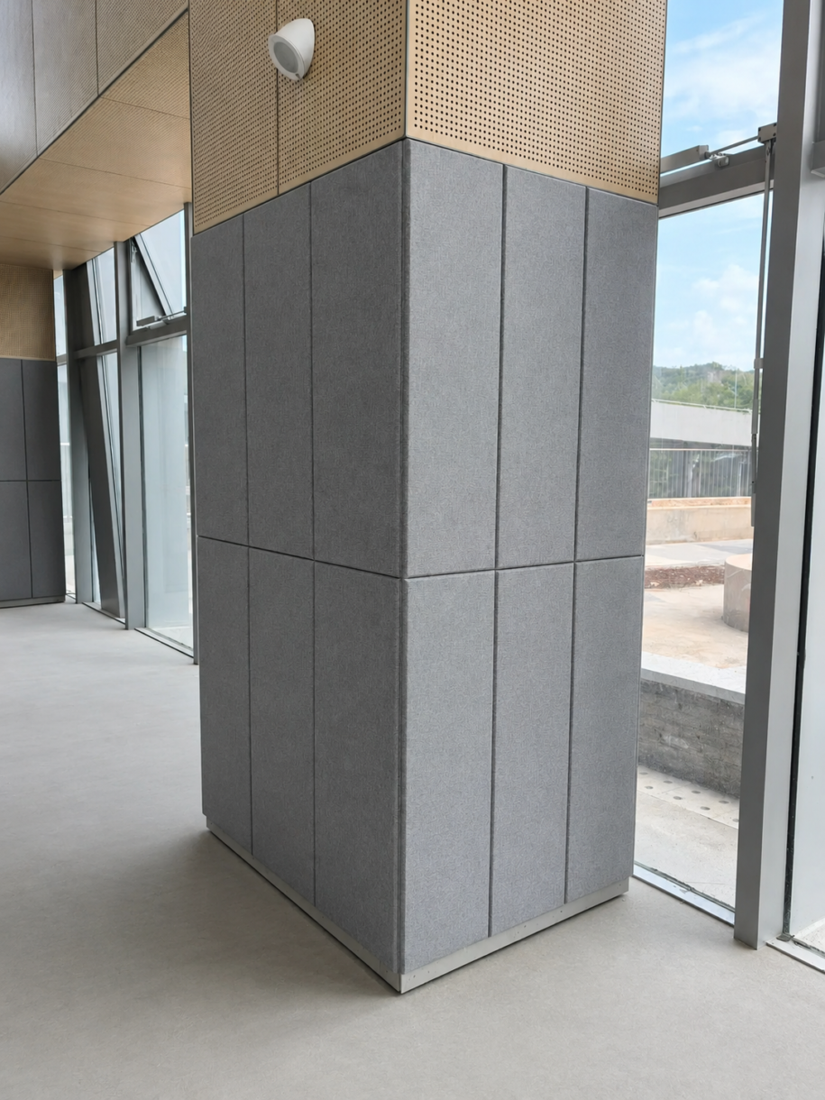 Grey fabric-wrapped fiberglass acoustic panels installed as structural column cladding in a modern commercial interior space.