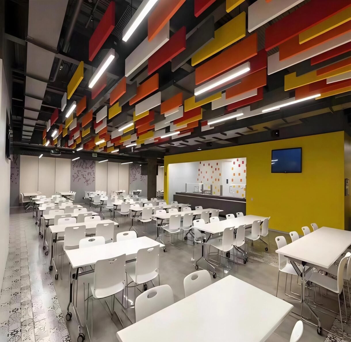 Colorful acoustic design baffle panels installed on an open ceiling in a school cafeteria to reduce noise and reverberation.