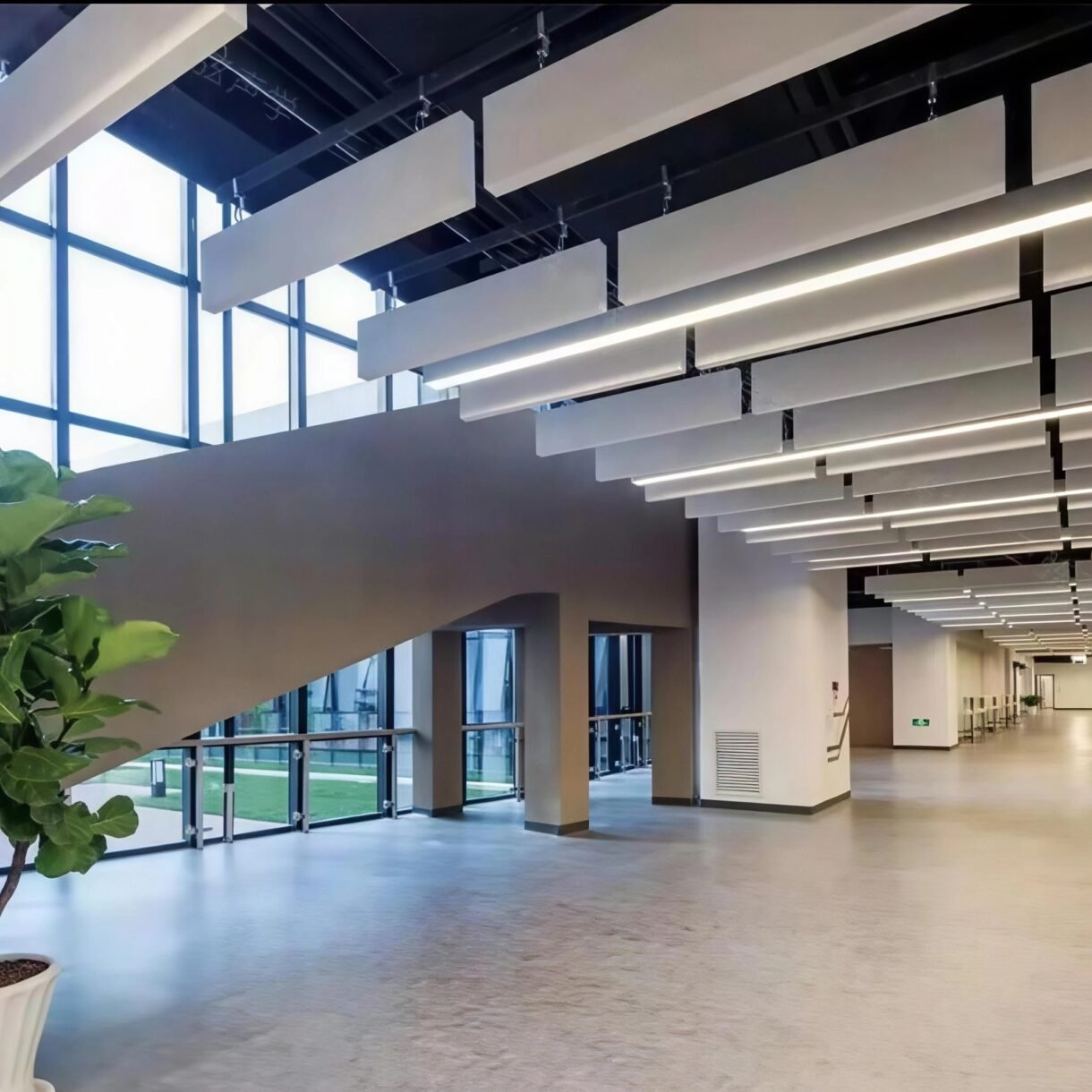 White fiberglass acoustic baffles suspended from the ceiling in a modern commercial lobby for noise control.